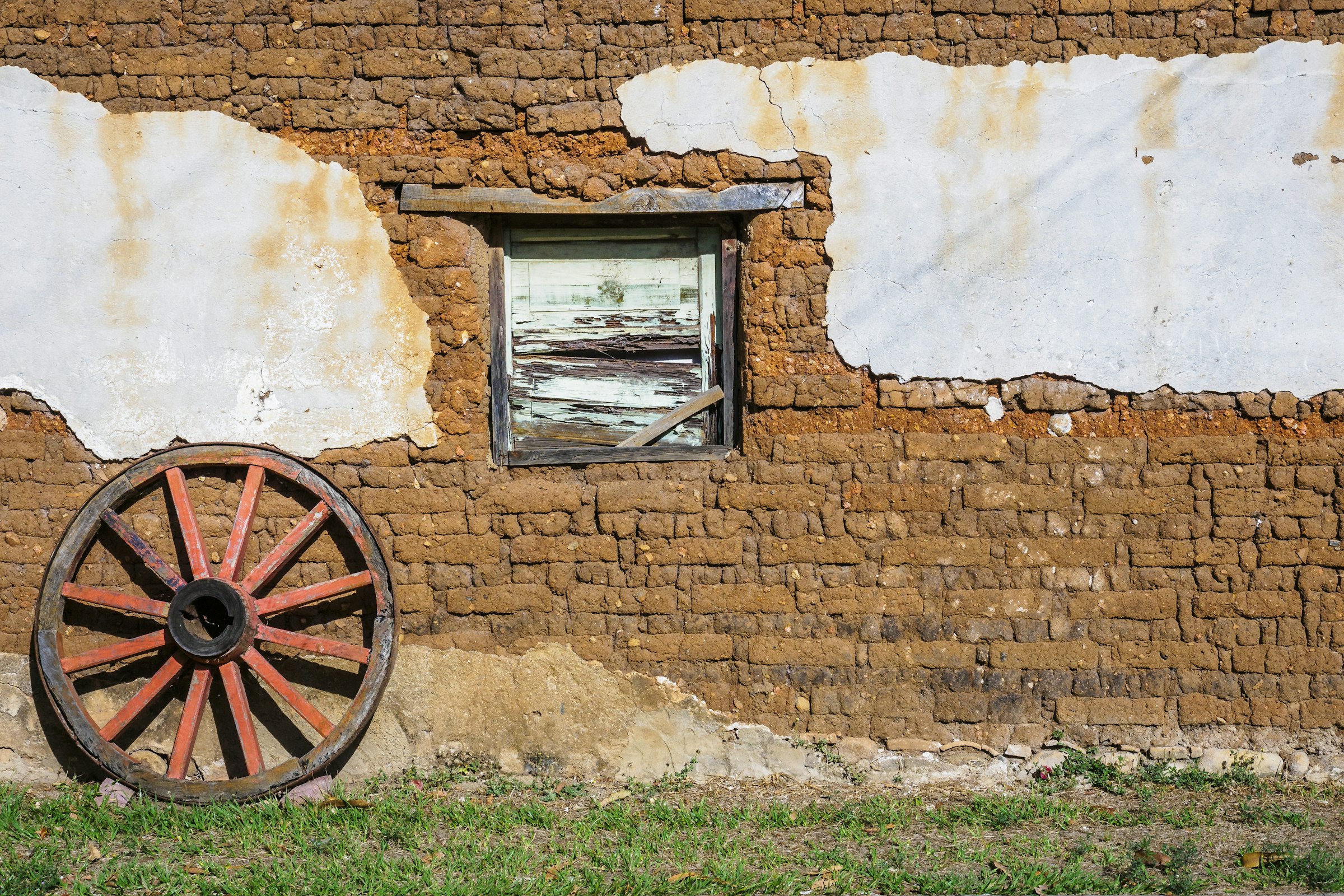 An earthen wall and a wagon wheel in Suchitoto